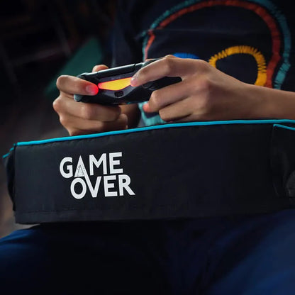 Person holding game controller over "GAME OVER" pillow