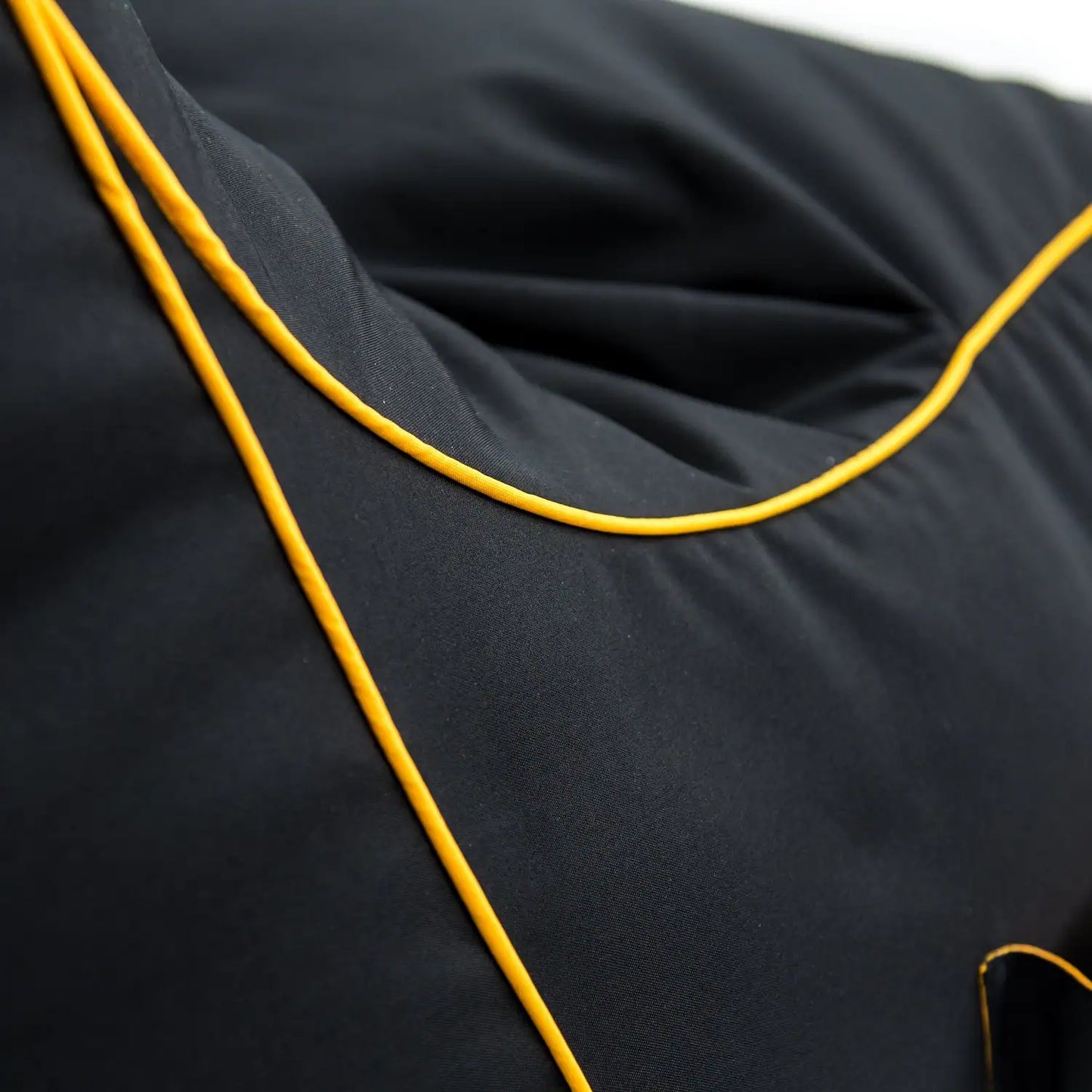 A close-up photo of a black fabric with yellow stitching.