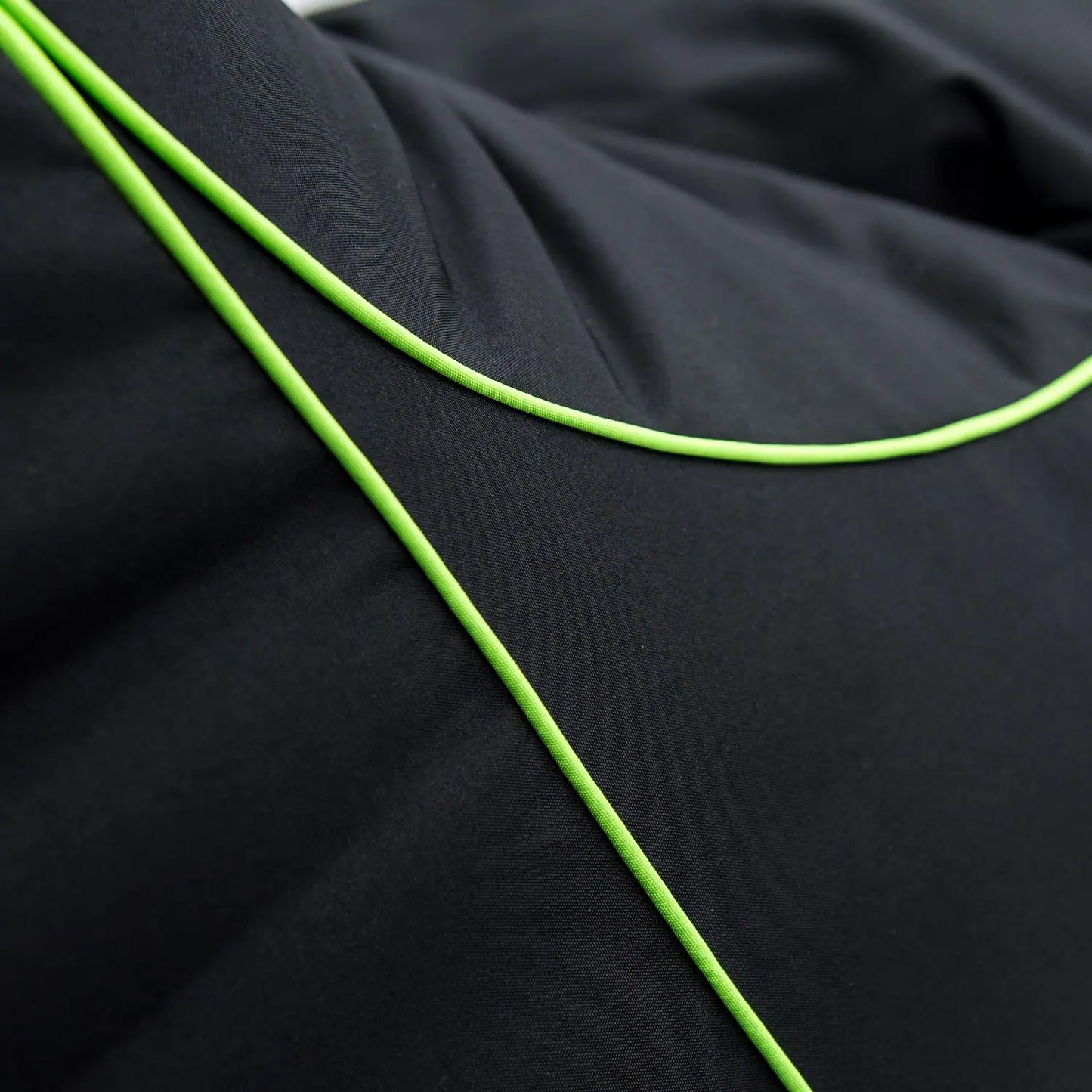 Black fabric with green stitching, close-up.