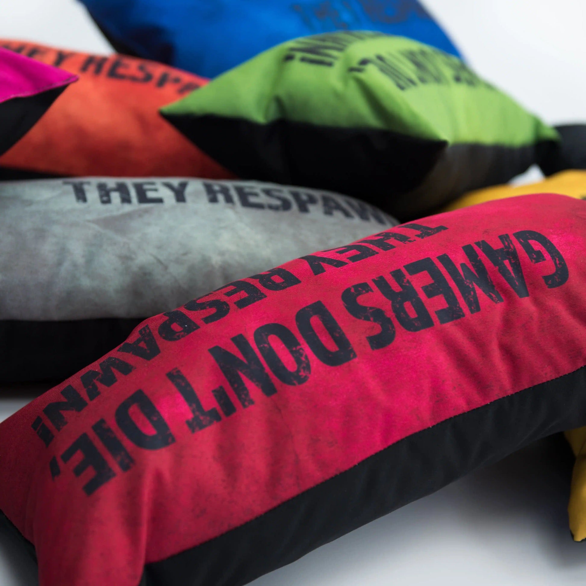 A stack of colorful pillows with the words "GAMERS DON'T DIE THEY RESPAWN" on them.